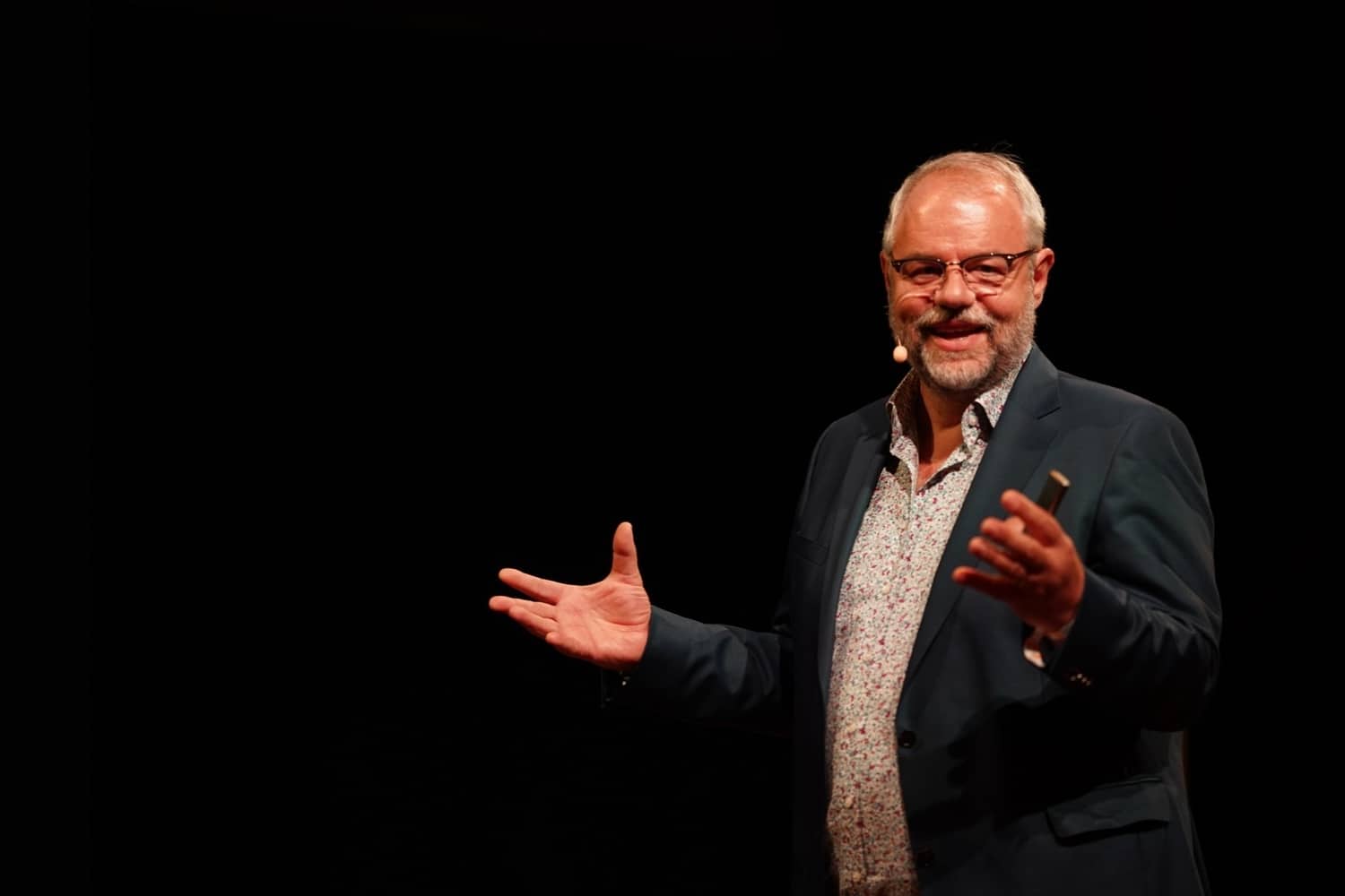 Mario Fischer steht auf einer Bühne vor schwarzen Hintergrund und hält einen Vortrag zum Thema "Arbeitsmoral der Generation Z"